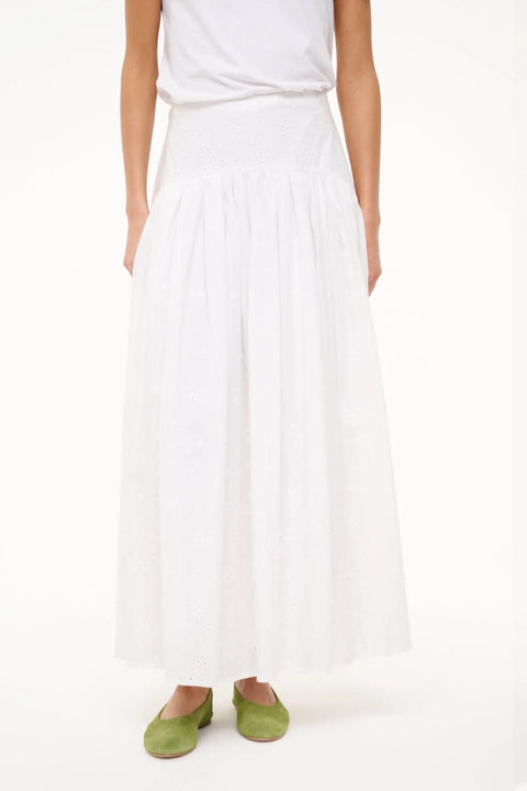 Close up of a woman wearing a white eyelet maxi skirt with a curved yoke waist, paired with green flats. 