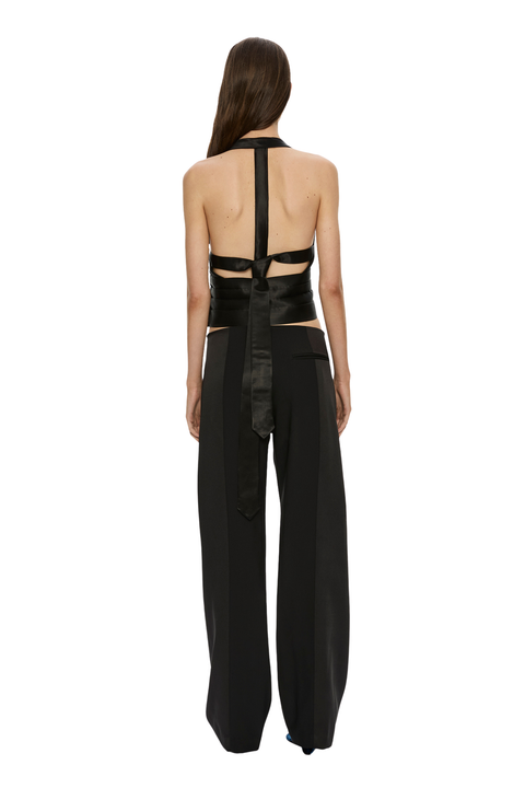 A model shown from the back wearing a black halter top with a wide satin back panel and matching wide-leg trousers, set against a plain white background.