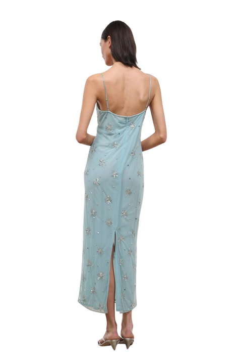 A woman wearing a light blue long dress with silver embellishments and a slit in the back