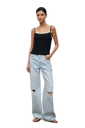 A model wearing a black ribbed knit camisole top, paired with light-wash distressed wide-leg jeans and brown sandals, set against a plain white background.