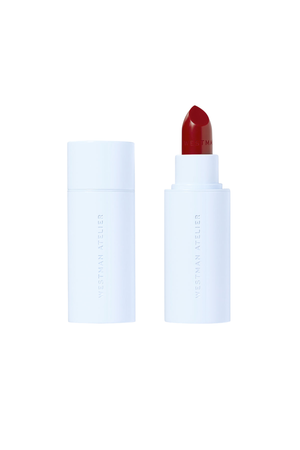 A lipstick bullet shown next to its cap on a plain white background. The lipstick bullet is a deep berry red, and the packaging is a matte white tube.