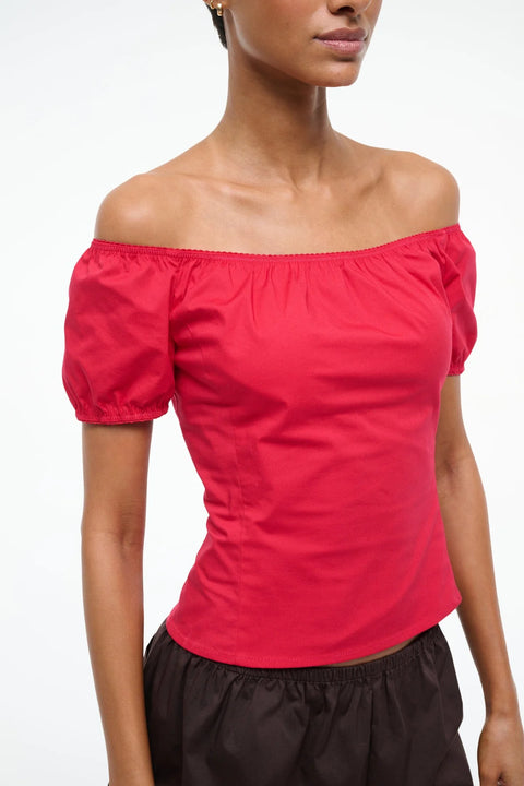 Close up of a woman wearing a bright red top that has puff short sleeves that can be worn on or off the shoulder. 