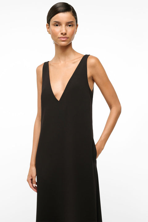 Close up of a woman wearing a deep-v black maxi dress. 