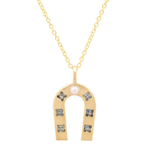 Gold horseshoe-shaped pendant with blue sapphires on a white background