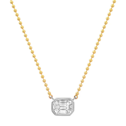 An illusion diamond necklace made up of smaller diamonds that resemble a large emerald cut diamond set in a  white gold bezel setting and attached to a yellow gold bead chain. 
