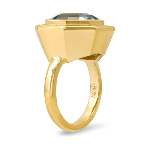 Ghost image of the side profile of a large aquamarine and diamond ring that features a gold bezel setting. 