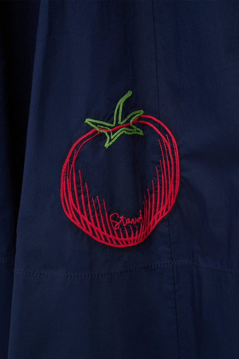 Detail shot of red and green embroidery depicting the shape of a tomato on a navy midi dress. 