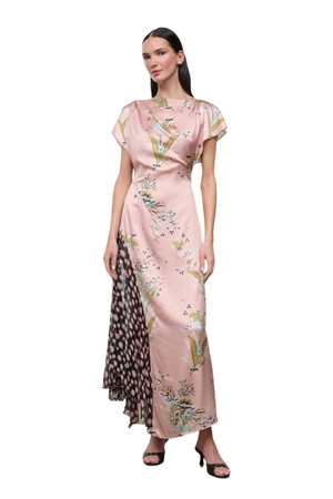 A woman modeling a floor-length pink dress with a floral print and a contrasting patterned side panel, photographed against a plain white background.