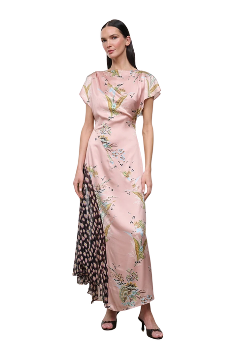 A woman modeling a floor-length pink dress with a floral print and a contrasting patterned side panel, photographed against a plain white background.