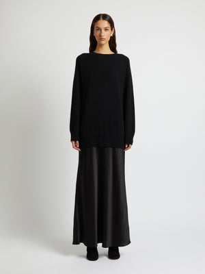 Woman wears black long sleeve sweater dress with silk skirt.