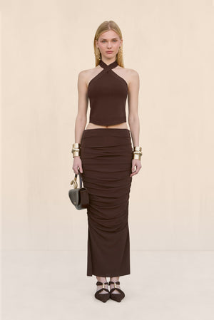 Woman wearing a brown knit tank top that features a halter neck, paired with a brown maxi skirt. 