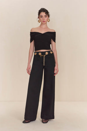 Woman wearing a black knit off the shoulder crop top paired with black wide leg jeans. 