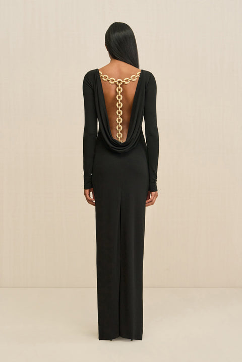 Black evening gown with gold chain detail on a beige background