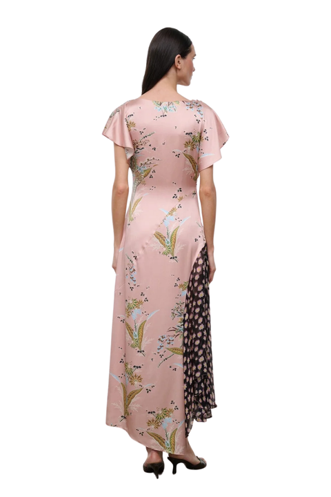 A woman shown from the back wearing a long pink dress with a floral print and a contrasting black side panel with a pink pattern, photographed against a plain white background.