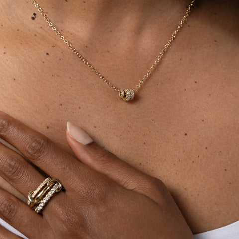 Woman wearing a Spinelli Kilcollin Norah ring that features a 1.7mm yellow gold band pave with diamonds, a 2.3mm yellow gold band, and a 2.8mm yellow gold band pave with diamonds, connected by two yellow gold connectors. 