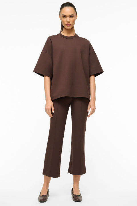 Woman wearing an oversized brown t-shirt with matching cropped flare brown pants. 