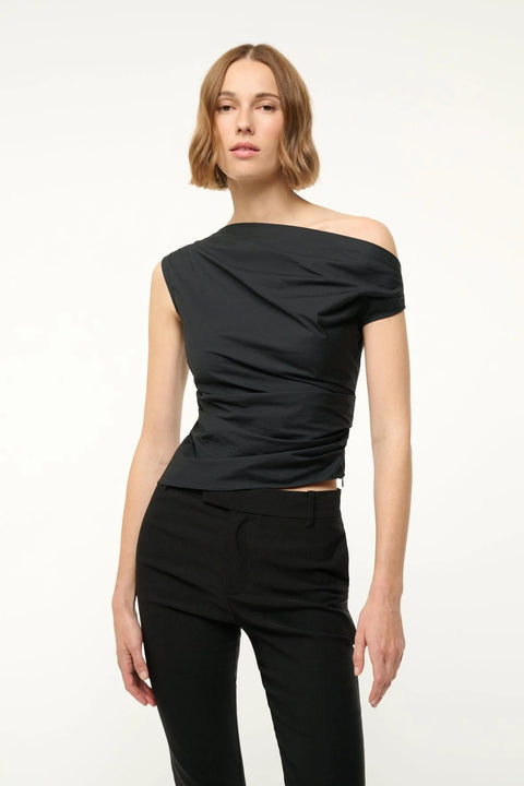 Close up of a woman wearing a black off-the-shoulder top that features asymmetrical ruching and hem, paired with black pants. 