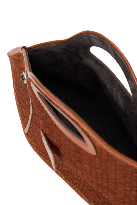 Close-up of a brown textured leather clutch bag with cutout handles and a dark interior lining, shown on a white background.