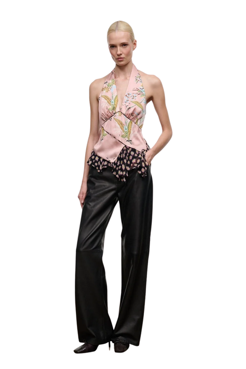 A model wearing a sleeveless halter top with a pink floral wrap design and black wide-leg pants, photographed against a solid white background.