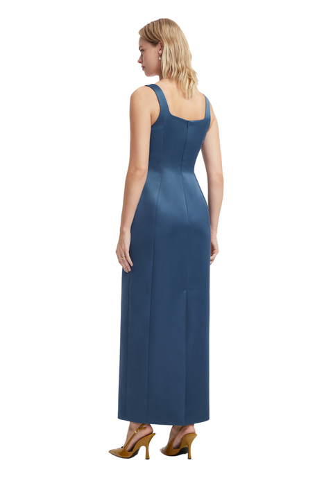 A woman modeling a sleeveless, floor-length blue dress from the back, shown against a plain white studio background.