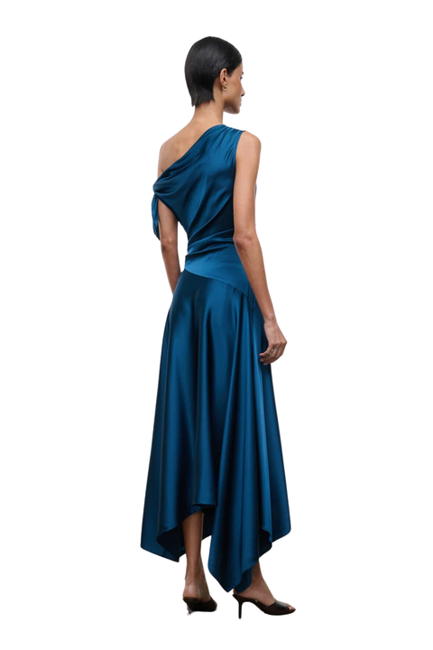 A woman modeling a teal blue one-shoulder satin midi dress, shown from the back against a solid white background.