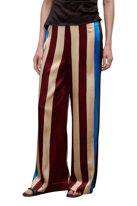A person wearing wide-leg trousers with vertical stripes in burgundy, beige, and blue, paired with a dark top and sandals, shown against a plain white background.