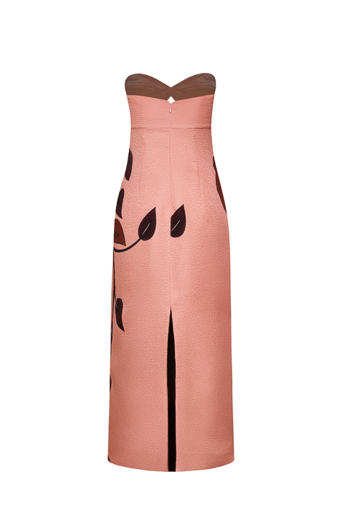 A strapless midi dress in a dusty rose pink color, featuring a sweetheart neckline, a back slit, and a black leaf pattern printed on the side.