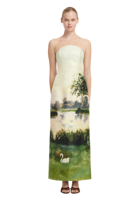 A strapless floor-length dress with a printed landscape design featuring a lake, trees, reeds, and a white swan, shown on a model against a plain white background.