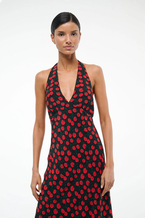 Close up of a woman wearing a black and red tomato print midi dress that features a halter neck and deep V. 