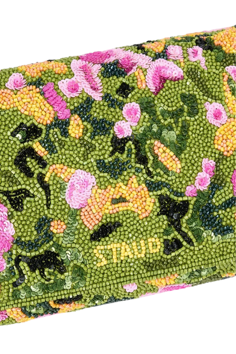 A close-up of a Staud beaded clutch bag featuring a vibrant green background adorned with pink flowers, yellow accents, and the brand name 'STAUD' beaded in yellow near the bottom.