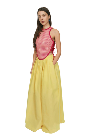 A woman wearing a patterned red top and a yellow long skirt