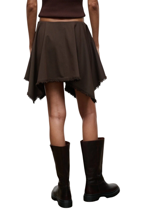 A person shown from the back wearing a dark brown flared asymmetrical skirt with frayed hems and dark brown knee-high boots against a plain white background.