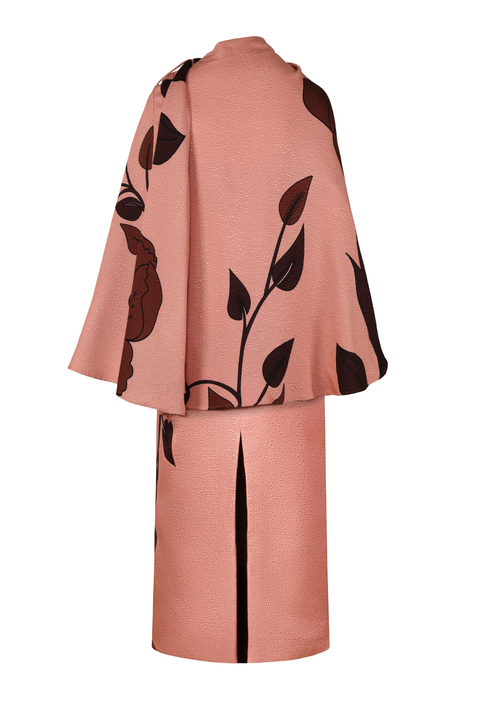 A peach pink dress with a large dark brown floral print and a matching cape, shown from the back against a plain white background.