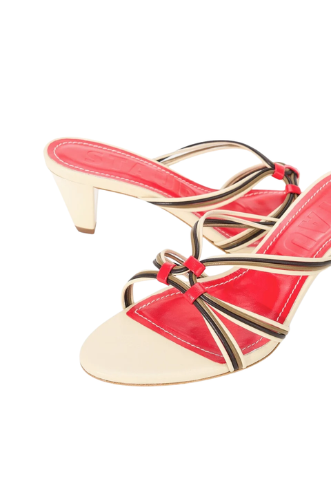 A pair of women's heeled mule sandals featuring a glossy red patent leather in-sole, a beige leather block heel, and thin metallic gold and black strappy details with red accents, shown against a plain white background.