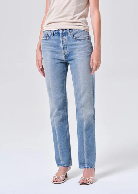 Person wearing light blue mid-rise, straight-leg jeans and a beige top on a white background off-center view 