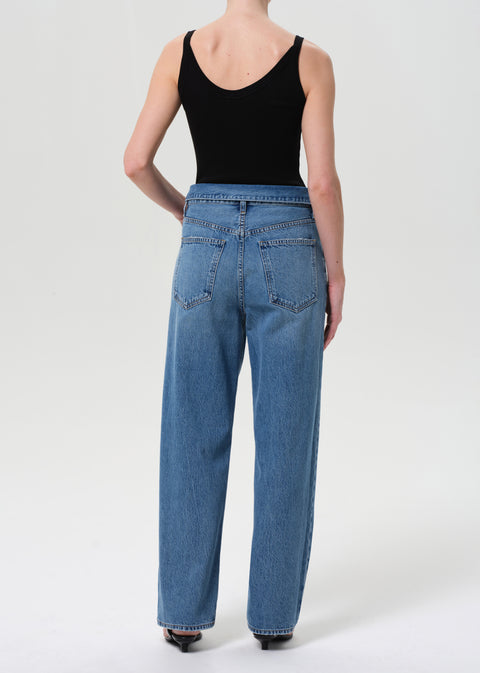 Back view of woman in black tank top and fold over jeans.