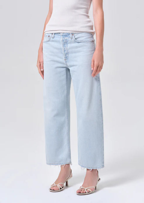 Person wearing mid-rise, wide-leg, light blue jeans and a white t-shirt on a plain background from the front