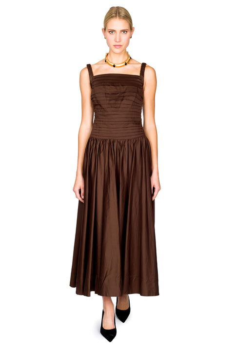 Woman stepping forward wearing a brown maxi dress on a white background