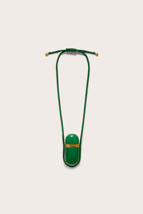 A green, functional amulet pendant with gold hardware on a green leather cord necklace. 