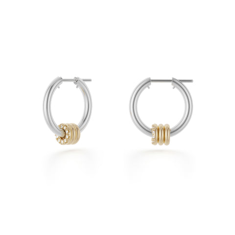 Ghost image of a pair of Spinelli Kilcollin Ara earrings that feature a mini sterling silver hoop adorned by three 18k yellow gold annulets, with the foremost one pave with white diamonds. 