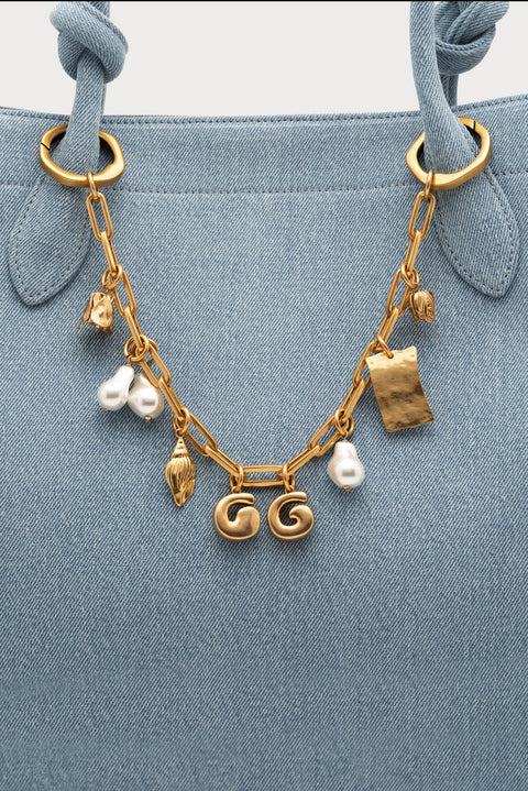 Gold bag chain with various charms on a light beige background on the back iteslf