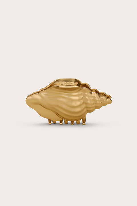 A gold-toned hair claw clip in the shape of a conch shell. 