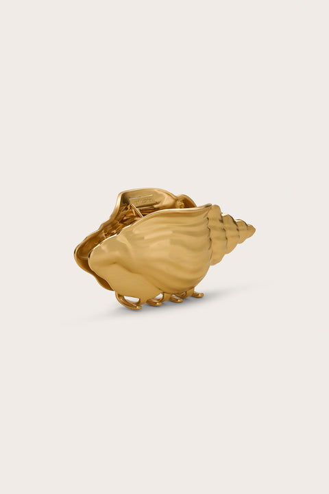 Side angle of a gold-toned hair claw clip in the shape of a conch shell.