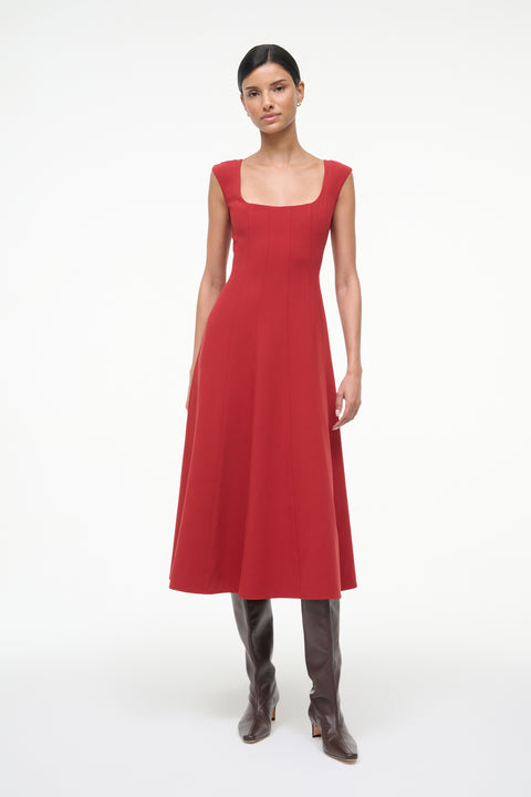 Woman wearing a red sleeveless midi dress with boots. 