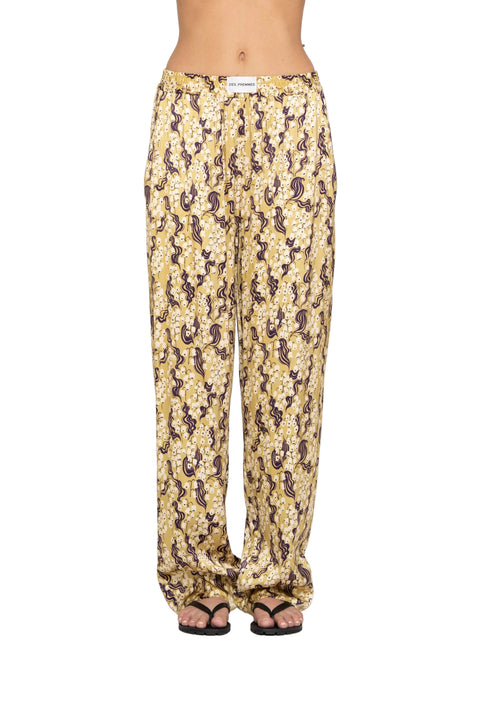 Detail shot of woman wearing pajama style yellow pants with ornate shapes.