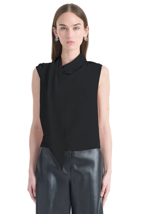 Woman wearing a black sleeveless top with a draped design on a white background