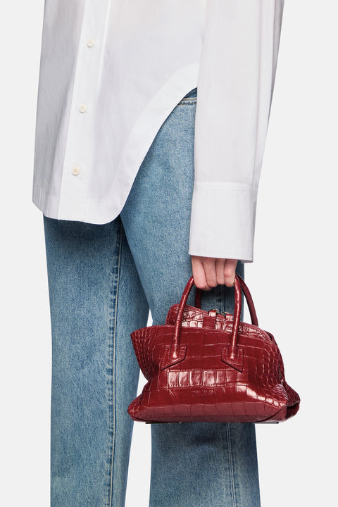 Person holding a red handbag with a white shirt and blue jeans
