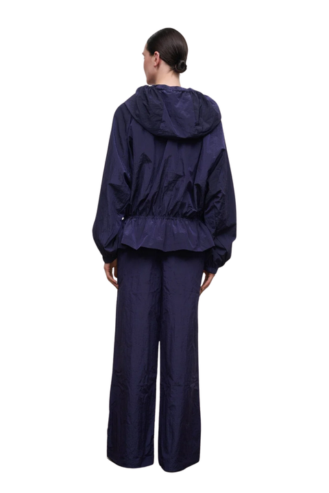 A model shown from the back wearing a dark navy blue hooded rain jacket and matching wide-leg pants against a plain white background.