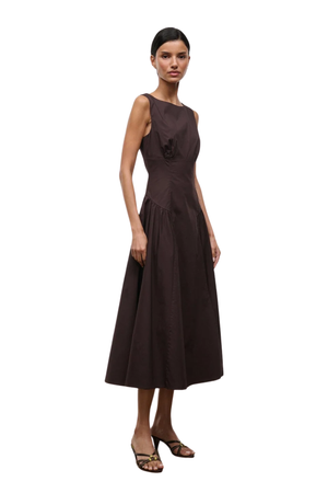 A woman modeling a sleeveless dark brown midi dress with a structured bodice, gathered skirt, set against a plain white background.