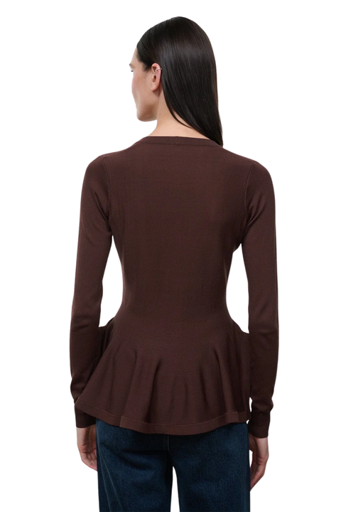 A woman viewed from the back wearing a dark brown long-sleeve top with a peplum waist and blue jeans, set against a plain white background.